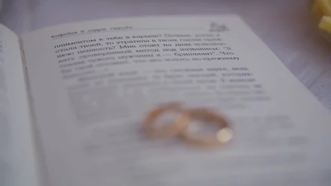 Close-up two gold wedding rings lie on page of the book with speaking text Stock Footage 100686491