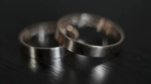 Close-up of two gold wedding rings lying on a wooden surface. On the decorations 스톡 동영상 103351448