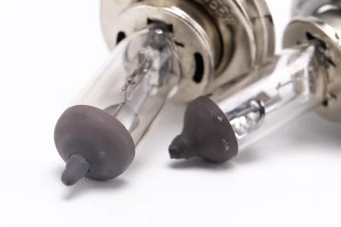 Close-up of Two Halogen Headlight Bulbs with Gray Caps on White Background. Stock Photos