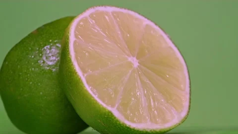 Close-up of two halves of fresh lime rotating on a green background Stock Footage 170555031
