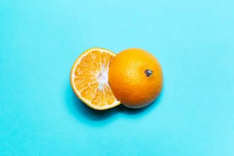 Close-up of two halves of orange fruit on background of cyan color. Stock Photos