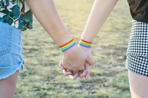 Close-up of two hands connected. Interlocking hands with lgtbi bracelets. Stock Photos