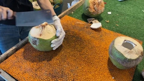 Close-up of two hands cutting and peeling a fresh coconut Stockbeeldmateriaal 323778427