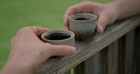 Close-up of two hands holding ceramic cups with pu-erh Chinese tea... Vidéo 316915525