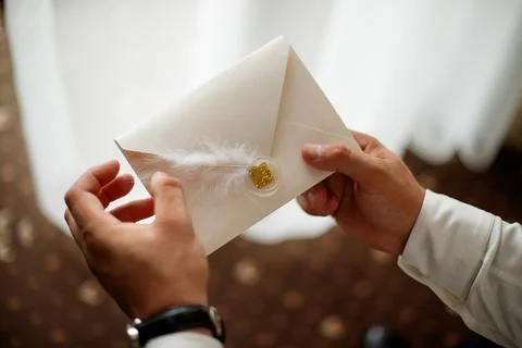 A close-up of two hands holding a romantic envelope containing a love letter Stock Photos