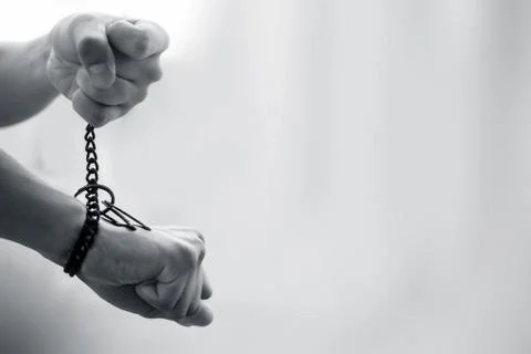 Close up of two hands one tied with a rusted chain and other pulling it shot  Stock Photos
