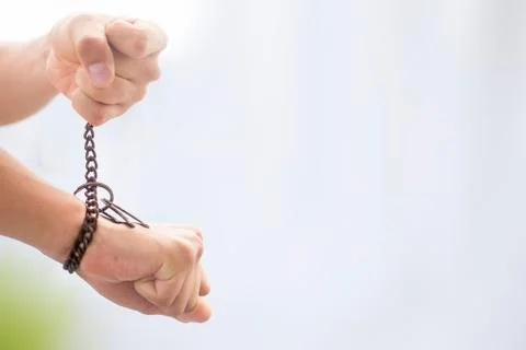 Close up of two hands one tied with a rusted chain and other pulling it shot  Stock Photos