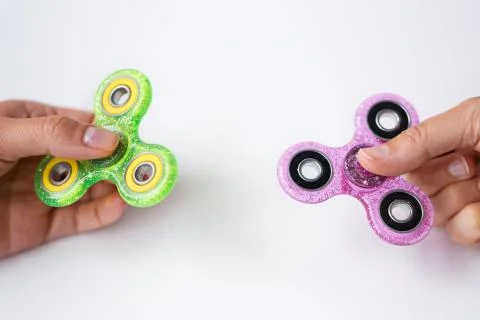 Close up of two hands playing with fidget spinners Stock Photos