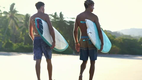 Close up of two handsome surfer guy friends with surfboards walking on beach  Stock Footage 108564480
