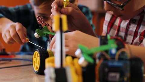 Close up of two happy boys using screwdrivers to put together robotic machines Stock Footage 82488821