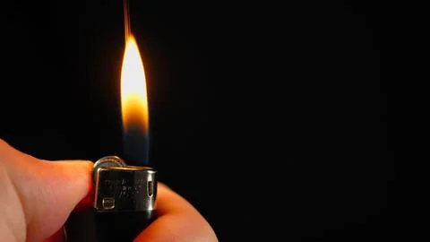 Close-up of two lighters slowly appearing in the frame one by one. The dark Stock Photos
