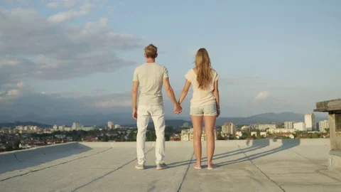 CLOSE UP: Two lovers standing on rooftop above the city, raising hands in sky Stock Footage 70715707