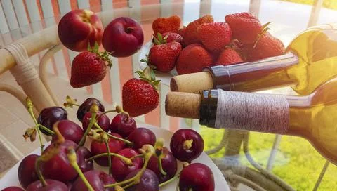 Close-up of two lying wine bottles, a pile of fruits and berries on a Stock Photos