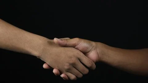 Close up two man shaking hand as agreement on black background. Stock Photos