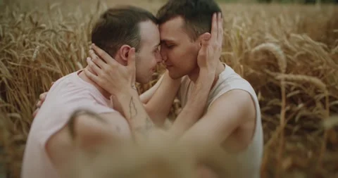 Close up two men gay hugging on field at the wheat smiling looking lovely at Stock Footage 200956839