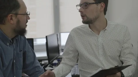 Close up of two men in glasses talking in office Stock Footage 97351927