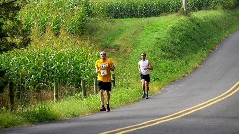 Close Up of Two Men Running Exercising Racing Cornfield Country Road Stock Footage 71325598
