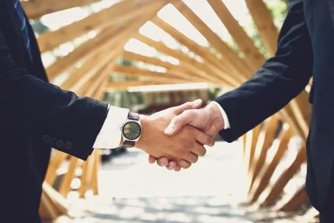 Close up of two men shaking hands while standing outdoors Stock Photos