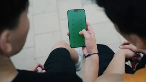 Close up of two men using a smartphone with a green screen outdoors Vidéo 347334254