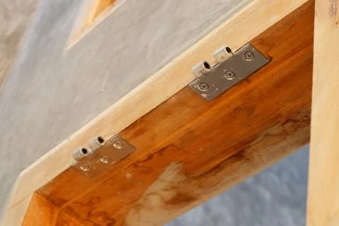 Close-up of two metal hinges installed on a polished wooden window frame mo.. Stock Photos