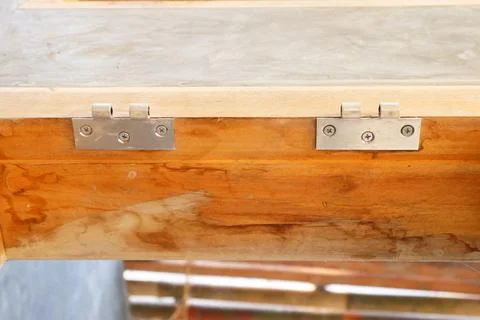 Close-up of two metal hinges installed side-by-side on a polished wooden wi.. Stock Photos