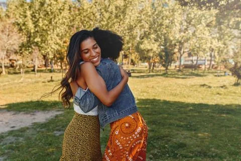 Close-up of two multiethnic happy pretty woman friends hugging each other in the Stock Photos
