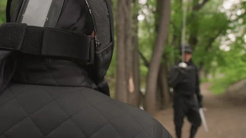 Close up two ninjas in black gear facing each other on forest path holding Stock Footage 345083344