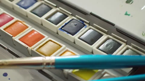 Close-up of two paint brushes laying on watercolor palette 스톡 동영상 265241958