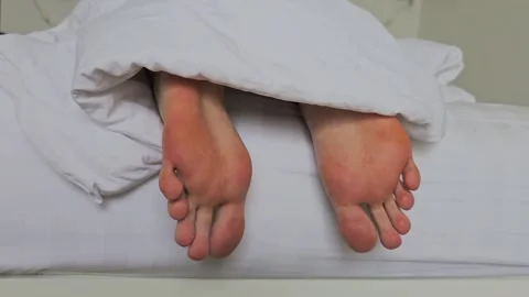 Close-up of two pairs of bare feet under a white blanket on a bed Stock Footage 282103602