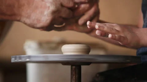 Close up two pairs of hands potter's and his young apprentice's making clay pot Stock Footage 150990397