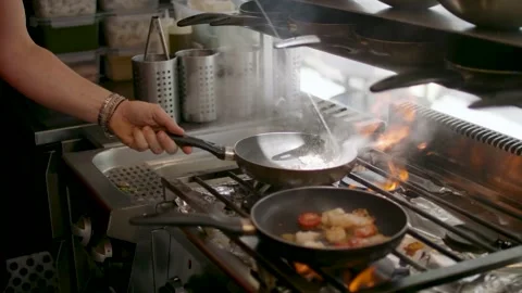 Close up two pans on fire with food inside throwing around the pan Stock Footage 203891541