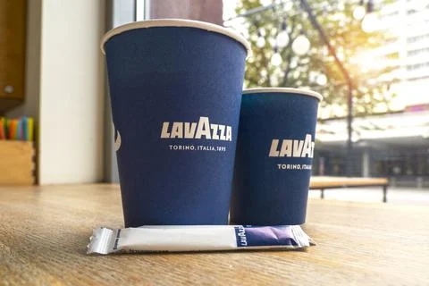 Close-up of two paper cups on a table with Lavazza coffee brand logotype Stock Photos