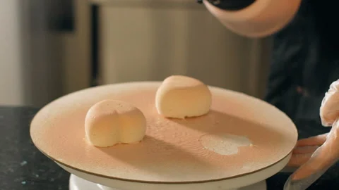 Close up of two pastry hearts being painted with pink syrop. Stock Footage 90228814