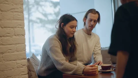 Close up of two people interacting at table in soft indoor lighting with coffee Stock Footage 346735699