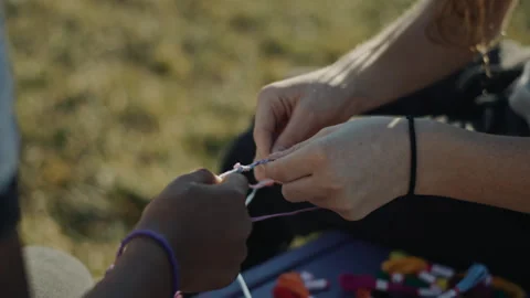 Close up of two people making friendship bracelets Video stock 334099213