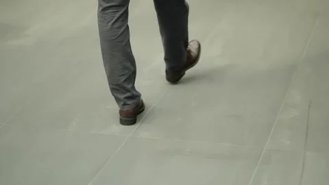 Close-up of two people walking across a light gray tiled hallway, focusing on Video stock 325670331