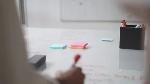 Close-up of two people writing on glass table while planning at office Stock Footage 114875615