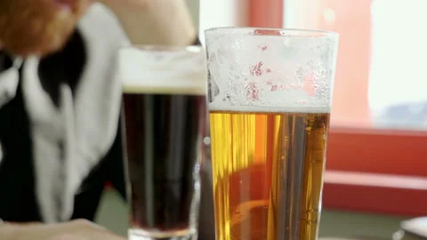 Close-up of two pints of beer standing on the table in a modern restaurant. 4K Video stock 92375911