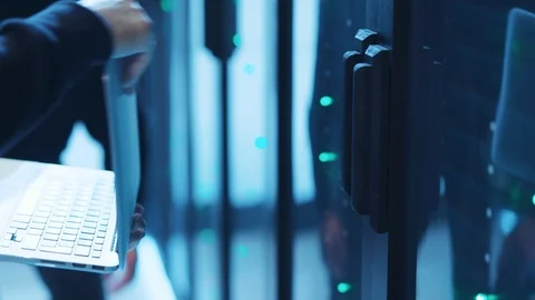 Close-up of two professional hackers sneaking into server cabinet, connecting Stock Footage 120605107