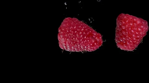 Close-up of two raspberries colliding with splashes of water Stock Footage 288193910