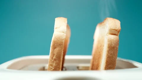 CLOSE UP: Two roasted bread slices jump out from a toaster on a blue background Stock Footage 149726045
