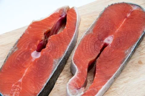 Close-up of two slices of raw red fish salmon on wooden board isolated on whi Stock Photos