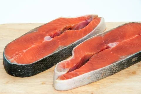 Close-up of two slices of raw red fish salmon on wooden board isolated on whi Stock Photos