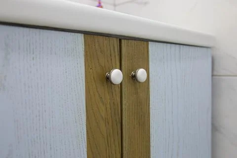 Close-up of two small round doorknobs on a bathroom cabinet 스톡 사진