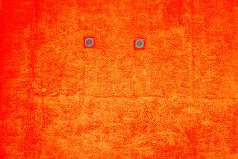 Close up of two small window with frame in the yellow wall. Orange wall textu Ilustración de archivo