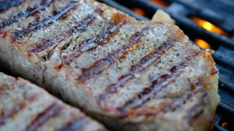 Close up of two steaks cooking on a grill Stock Footage 140066302