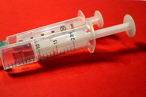 Close-up of two syringes on a red background. Stock Photos