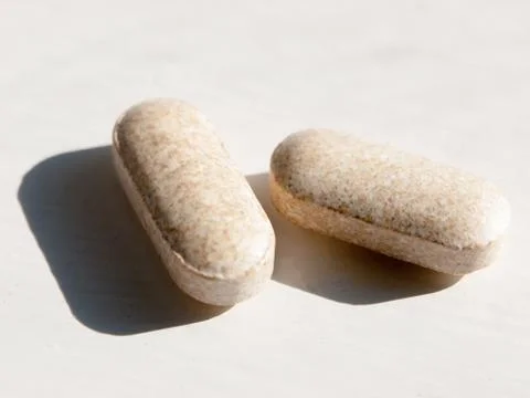 Close up of two tablets on white background health vitamins Stock Photos
