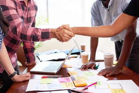 Close up of two tech engineers shaking hands at design launch meeting mobile app 写真素材