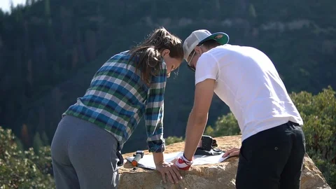 Close-up of two tourists a man and a woman with backpacks reading a map and look Stock Footage 101631708